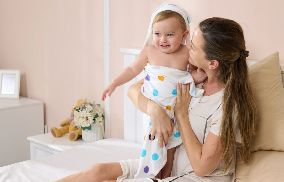 A cozy after-bath lifestyle image showing a baby wrapped in a soft hooded towel.