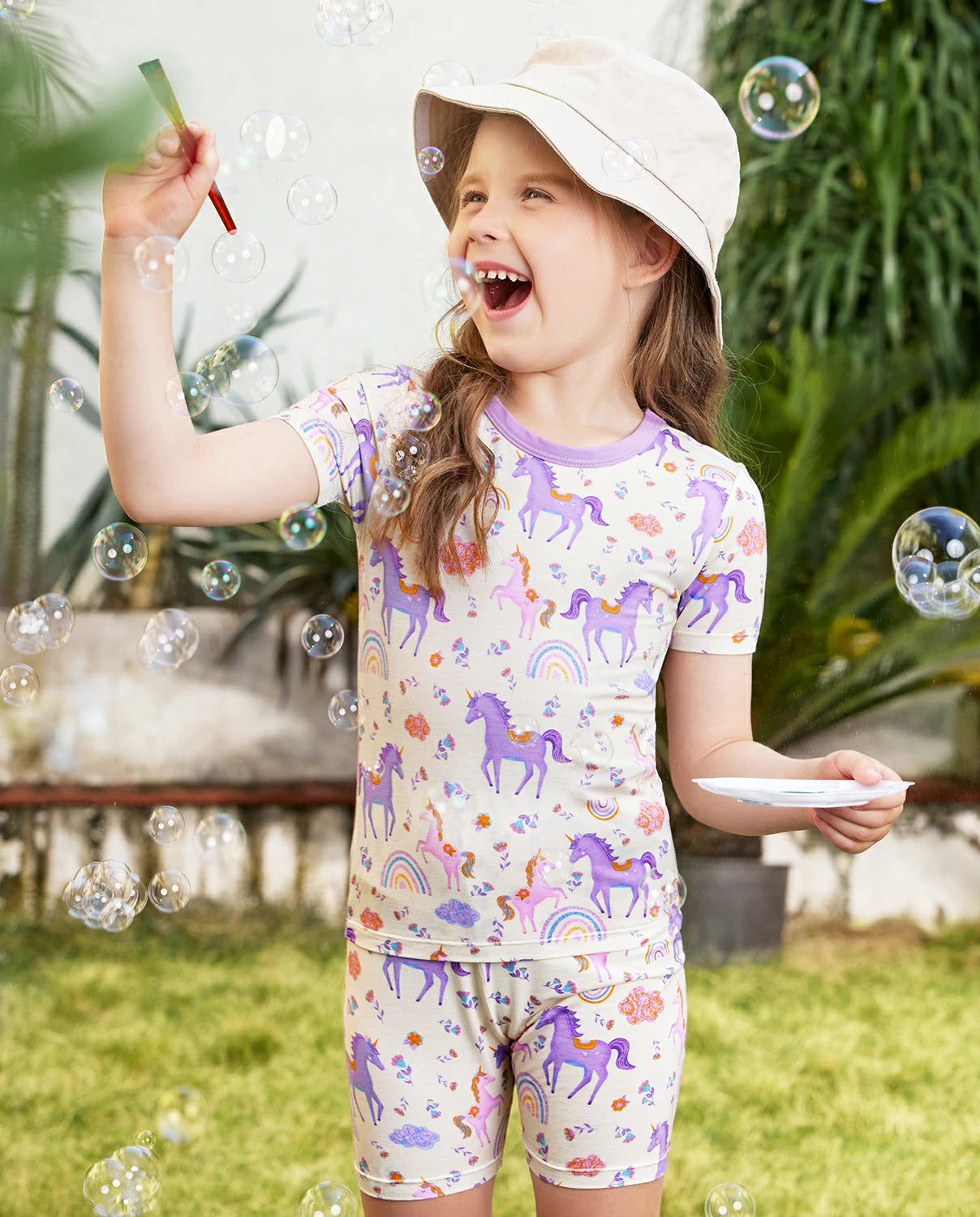Lavender Unicorn Short Two-Piece Pajama Set - child wearing the short pajamas while blowing bubbles outdoors