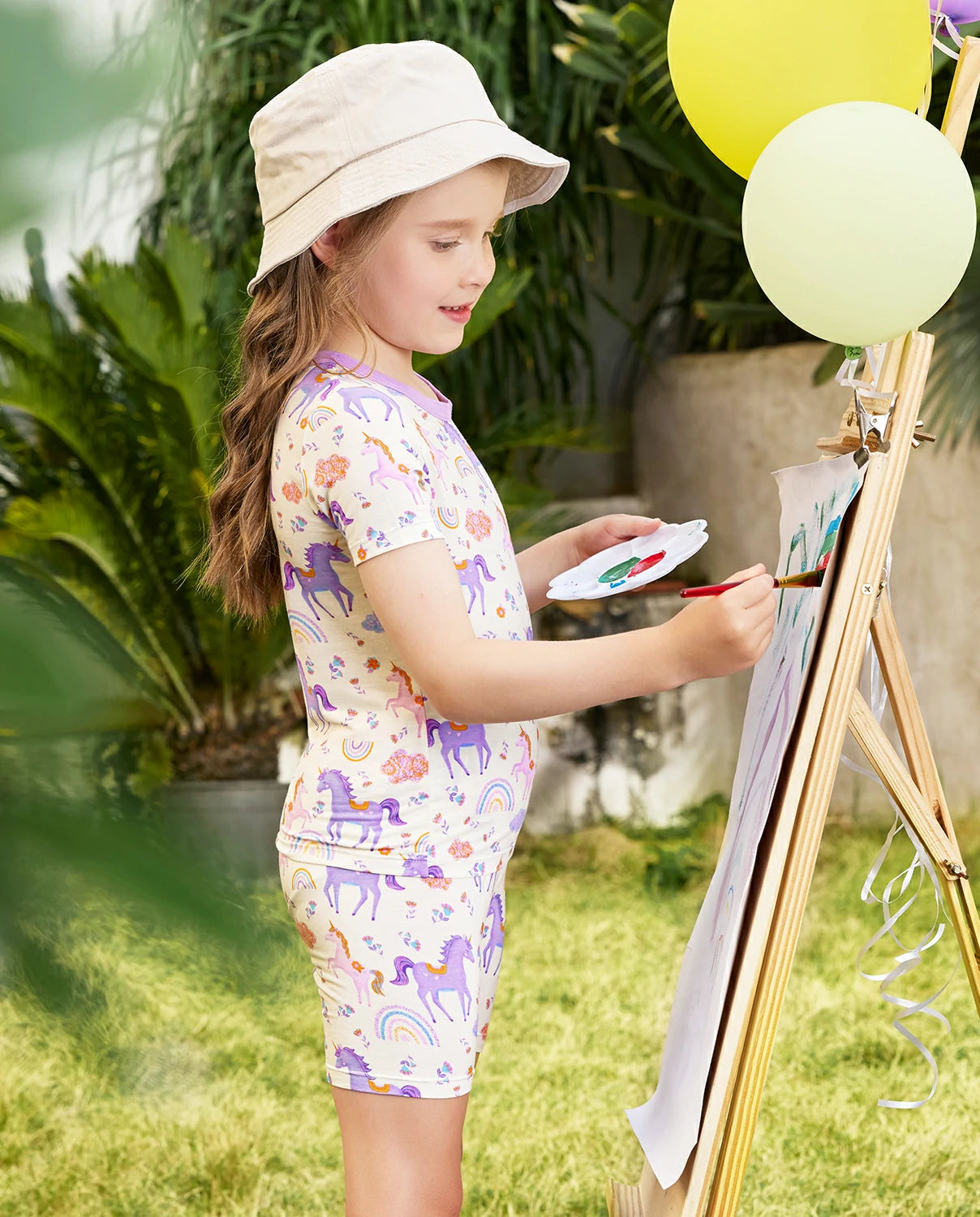 Lavender Unicorn Short Two-Piece Pajama Set - child wearing the short pajamas while painting, side view