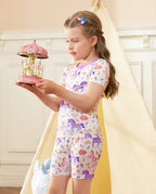 Lavender Unicorn Short Two-Piece Pajama Set - child wearing the short pajamas while holding a carousel toy