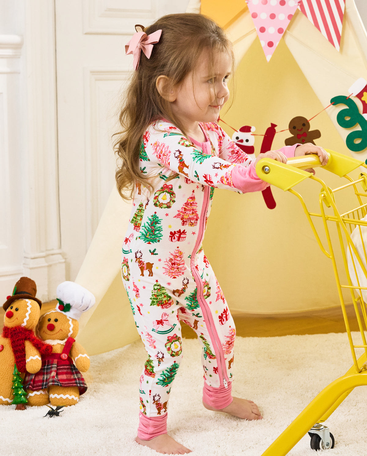 Child standing beside a yellow cart in the Blush Christmas zip-up romper.