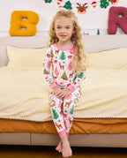 Child seated on bedding with crossed legs in Blush Christmas pajamas.