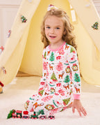 Child waving while seated by a play tent in Blush Christmas pajamas.