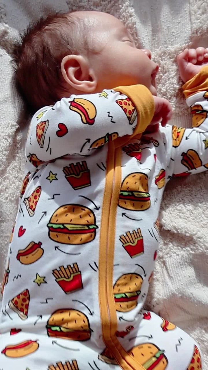A baby wearing a burger-and-fries print Babee Reshinee zip-up outfit.