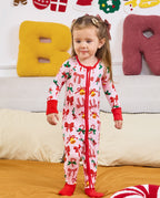 Child standing on bedding in the Christmas Bow romper with red cuffs.