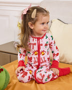 Child seated beside a sofa in the Christmas Bow zip-up romper.
