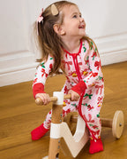 Child looking up while seated on a wooden tricycle in the Christmas Bow romper.