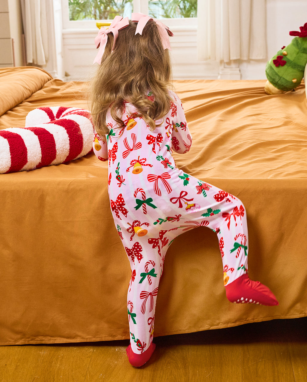 Rear view of a child crawling on bedding in the Christmas Bow romper.