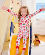 Child standing on a slide with arms out in Christmas Bow pajamas.