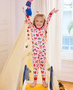 Child standing with a plush toy raised in Christmas Bow pajamas.