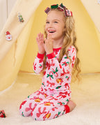 Child seated by a play tent and looking up in Christmas Bow pajamas.