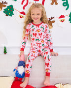 Child seated on a sofa with a plush toy in Christmas Bow pajamas.