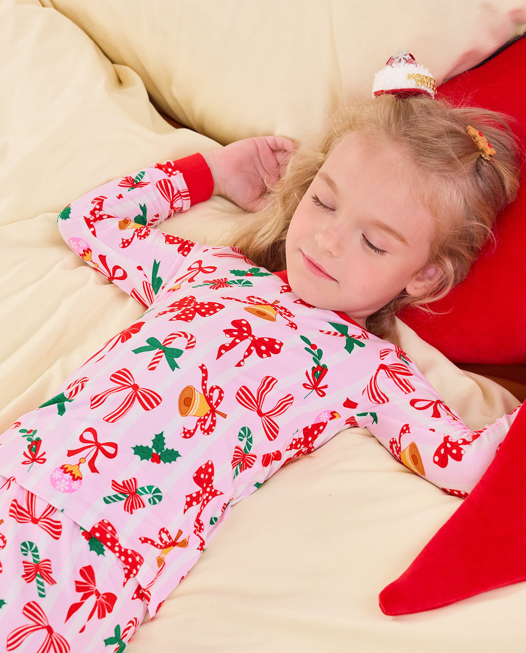 Child lying on bedding in the Christmas Bow long-sleeve top.