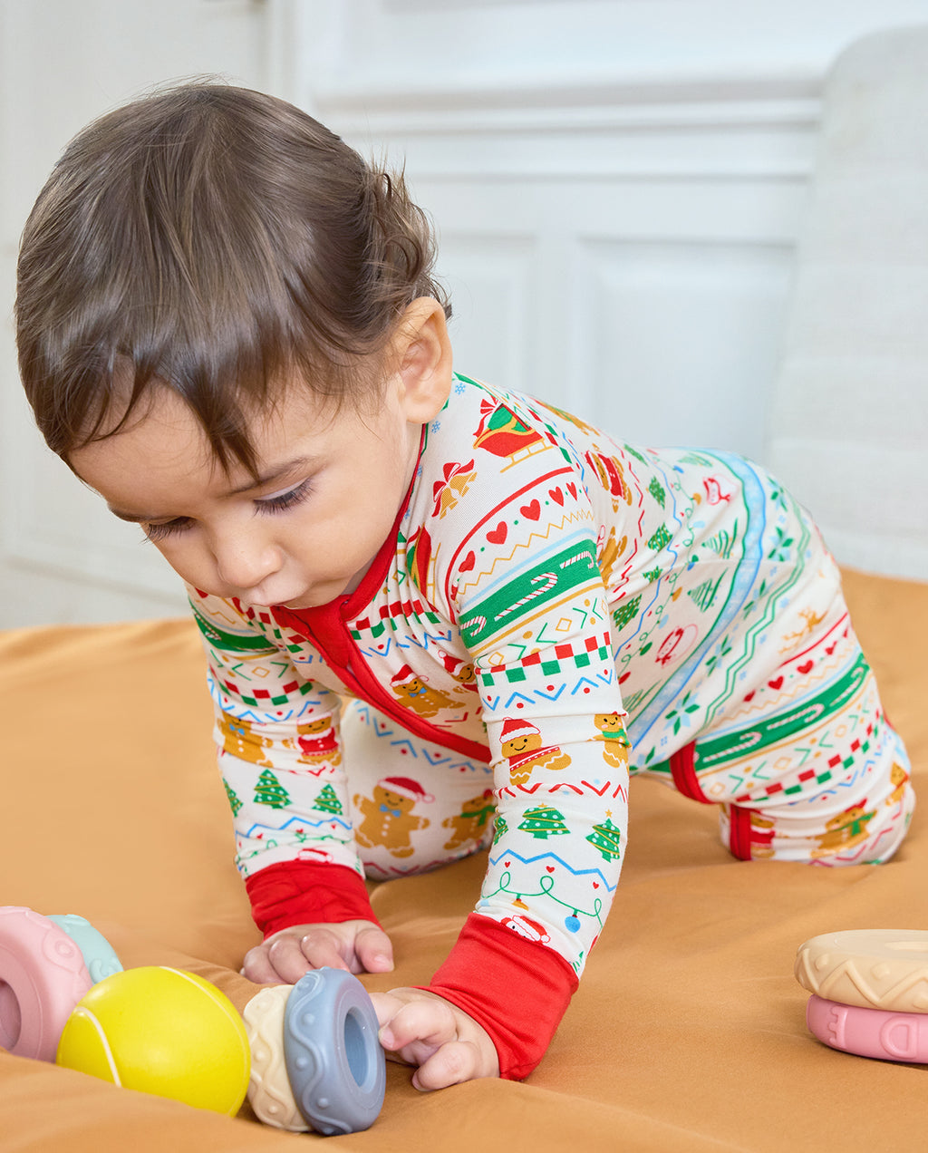 Baby crawling toward toys in the Christmas Fair Isle Bamboo Zippy with red sleeve cuffs