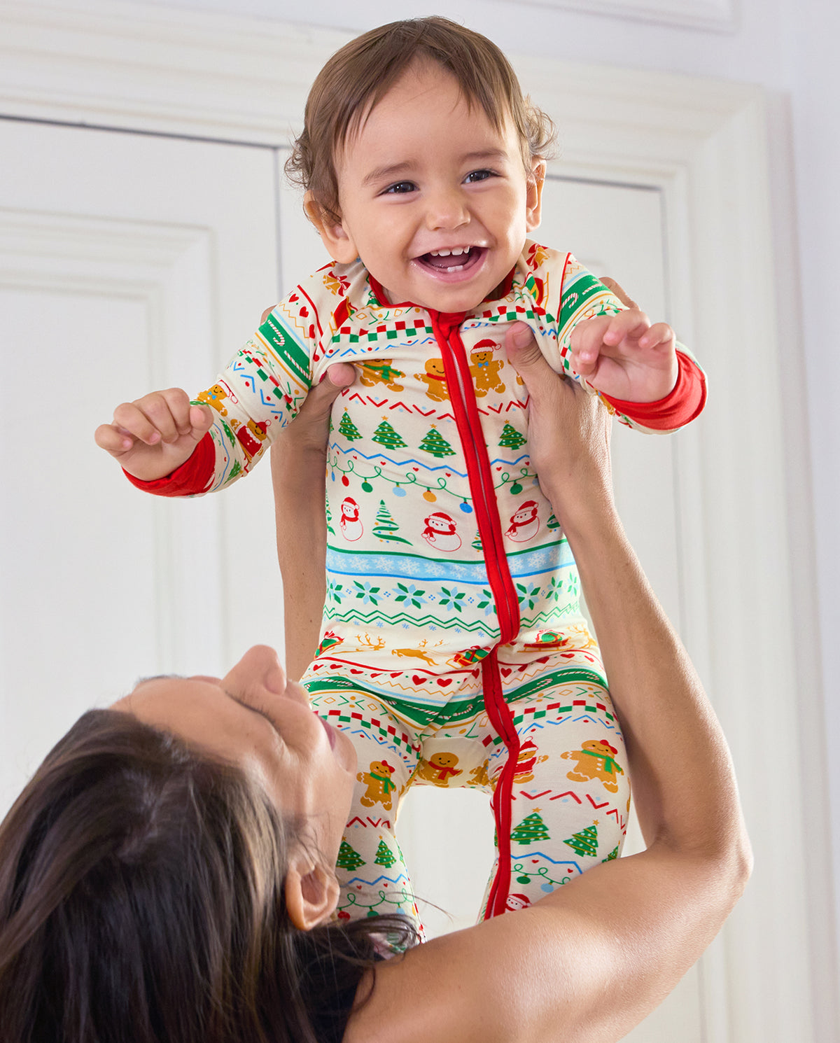 Smiling baby held up in the Christmas Fair Isle Bamboo Zippy with red zipper trim