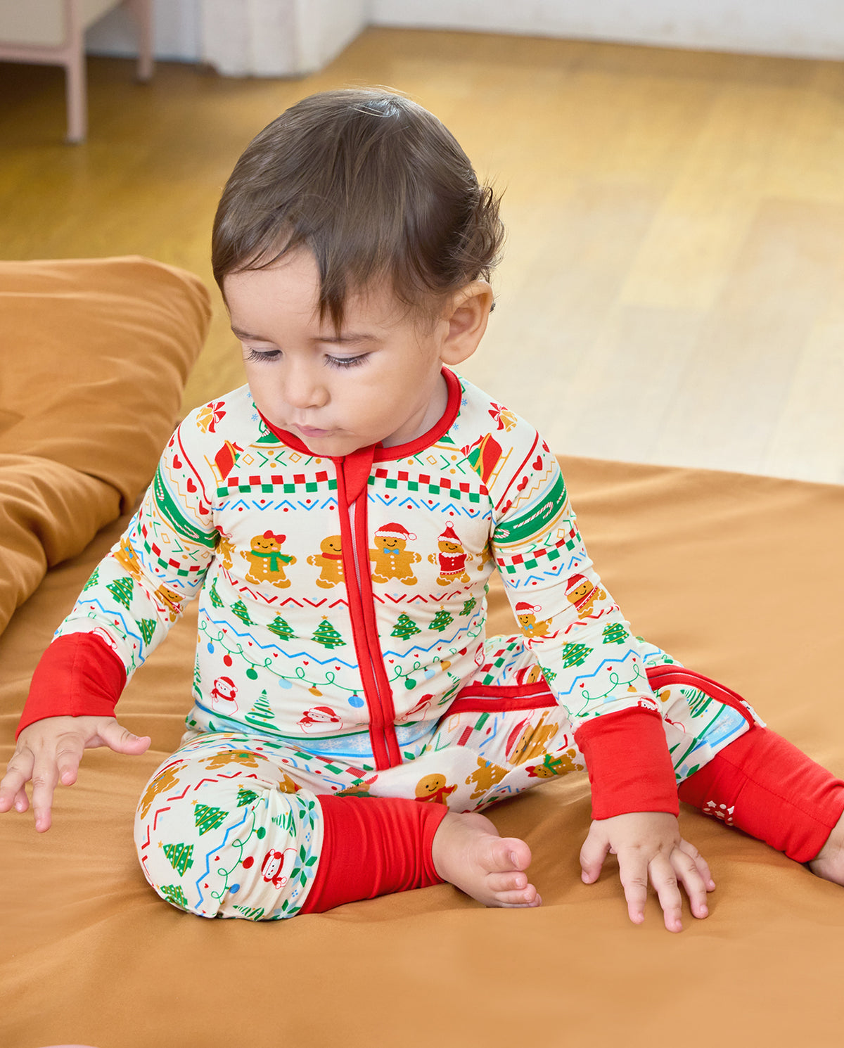 Baby sitting on a sofa in the Christmas Fair Isle Bamboo Zippy, showing the striped holiday print