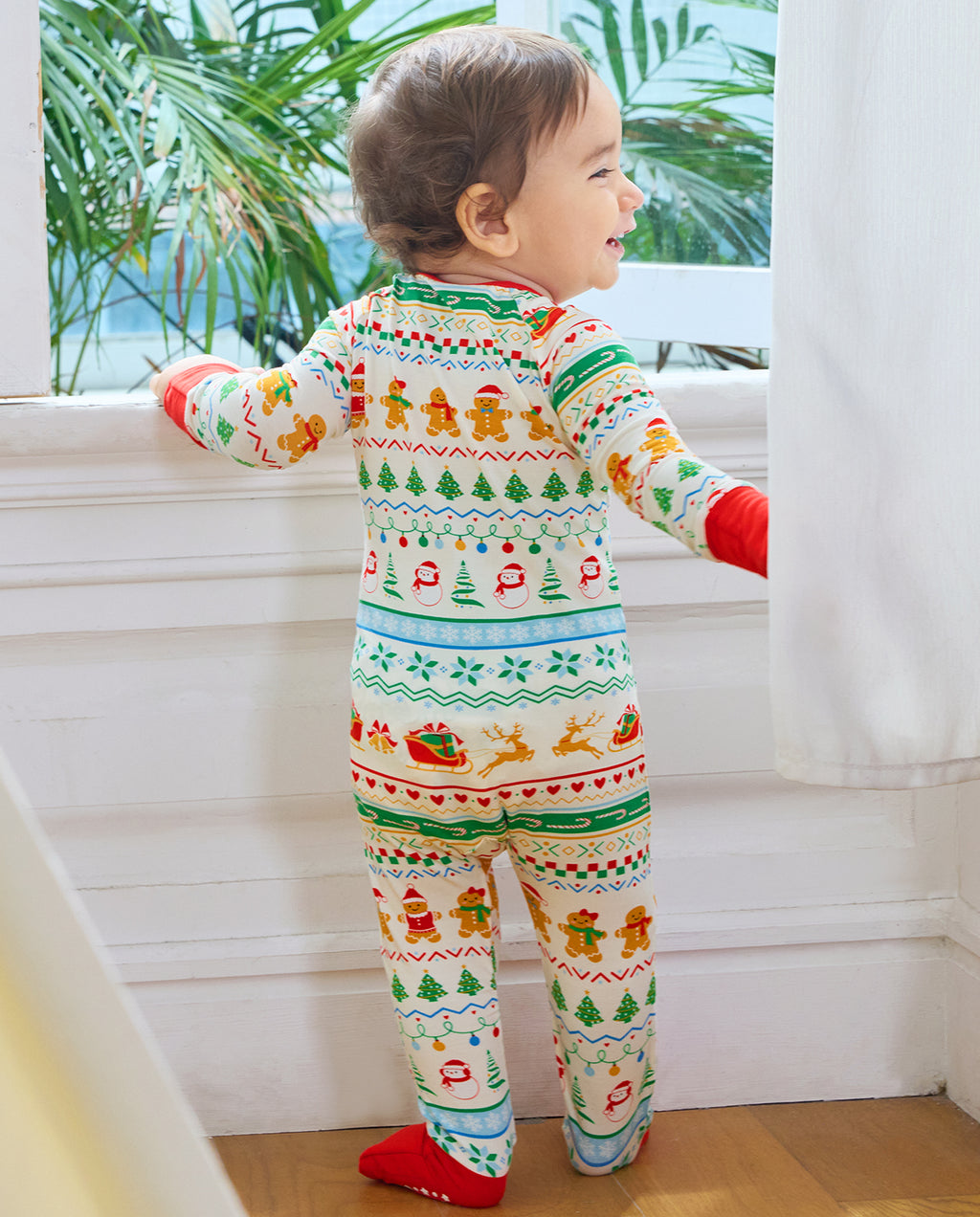 Back view of a baby standing by a window in the Christmas Fair Isle Bamboo Zippy