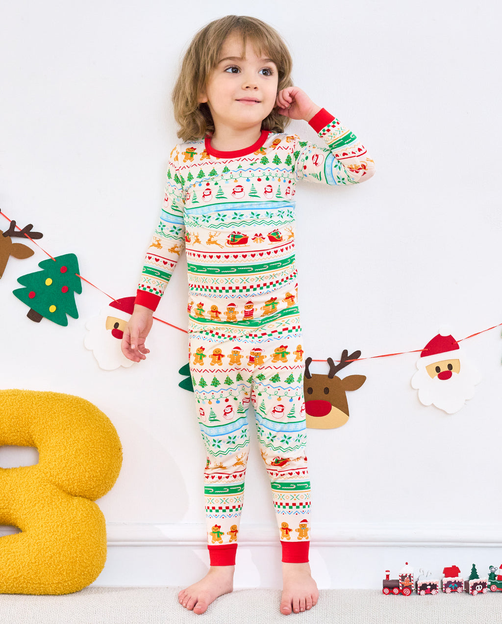 Child standing in Christmas Fair Isle two-piece pajamas with festive patterned rows and red trim
