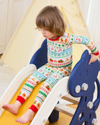 Child seated on a slide in Christmas Fair Isle long-sleeve top and matching pants