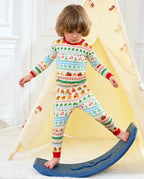Child wearing Christmas Fair Isle pajamas while standing beside a blue rocking toy