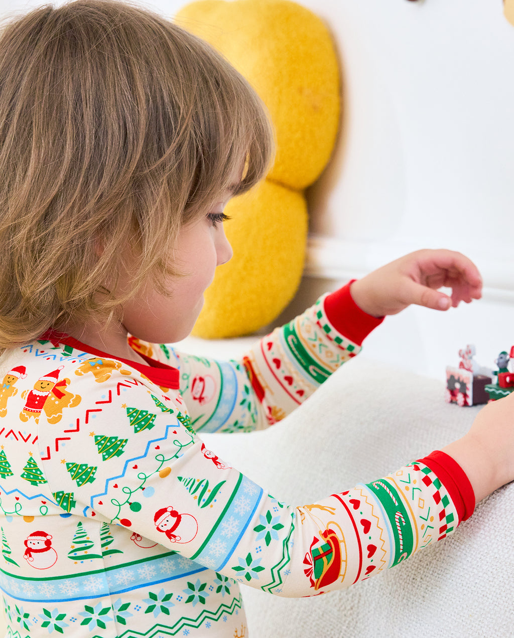 Child sitting sideways on a sofa in Christmas Fair Isle two-piece pajamas
