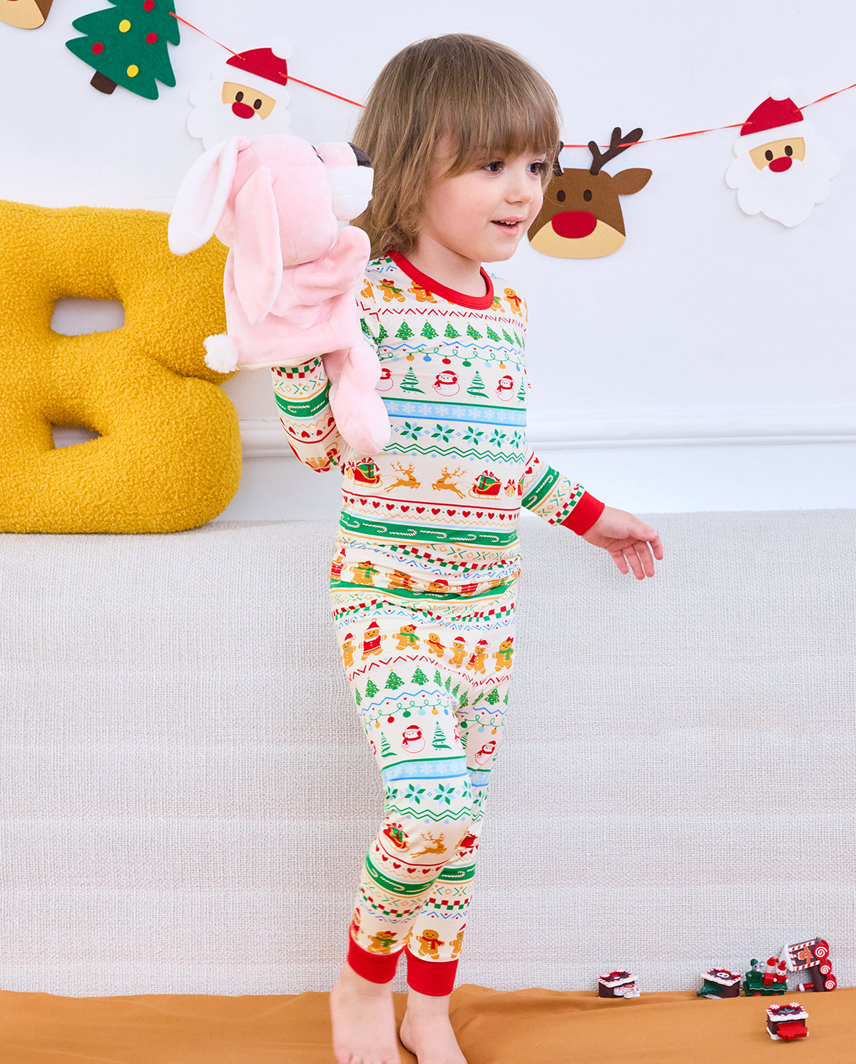 Child holding a pink toy while wearing Christmas Fair Isle long-sleeve pajamas