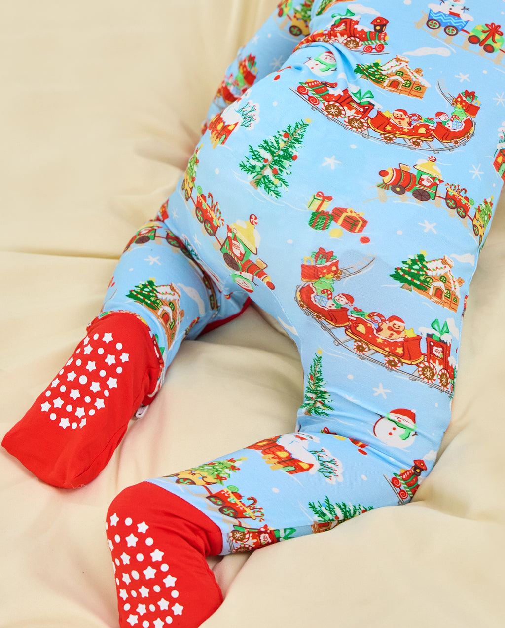 Reclining child in the Christmas Trains Bamboo Zippy, with both red soles and their white grip pattern facing the camera.