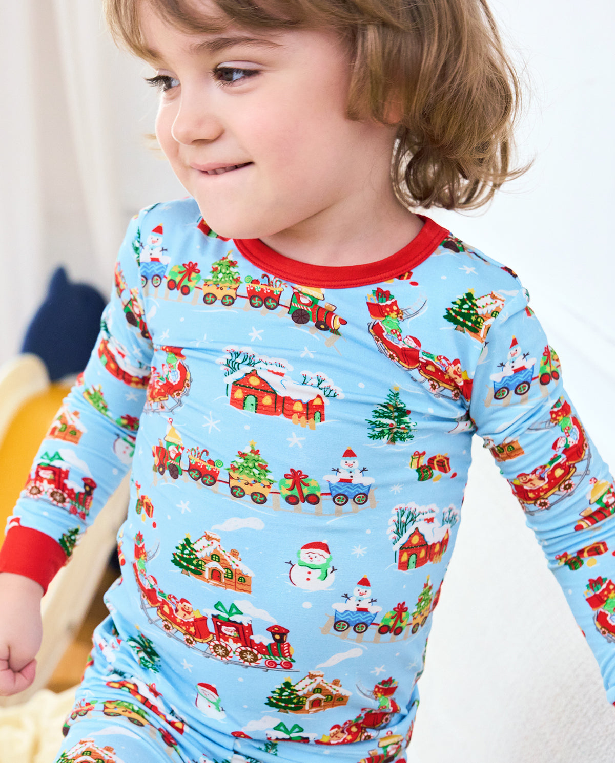 Side close-up of a seated child wearing the Christmas Trains long-sleeve top.
