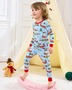 Child standing by a pink rocker beside a holiday play tent in Christmas Trains pajamas.