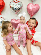Three children wearing babee Reshinee Createe Cozee custom bamboo pajamas with pink and red heart prints