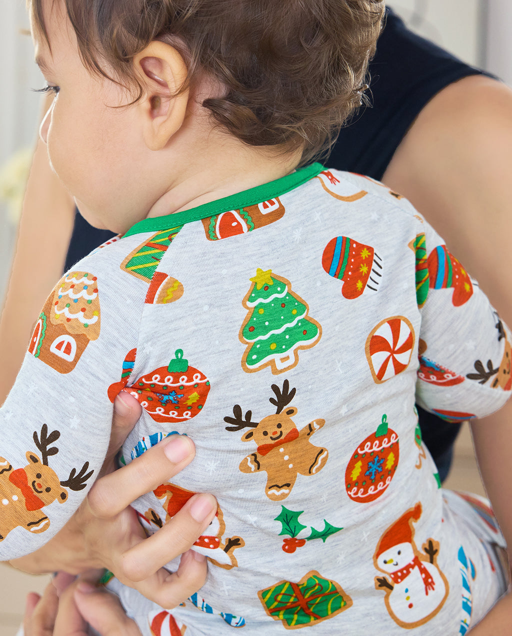 Close-up of the Gingerbread Gala print on a baby's back, with a gingerbread reindeer, cookie tree and red ornament