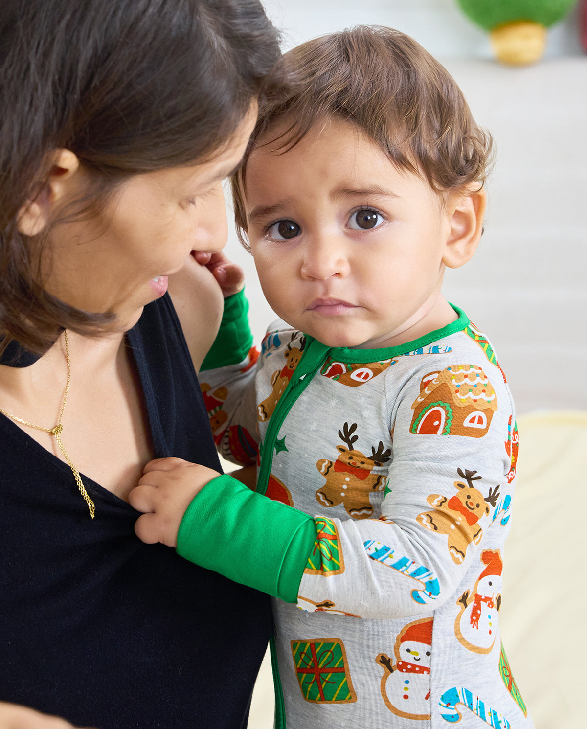 Baby held by an adult wearing the Gingerbread Gala Bamboo Zippy with green cuffs and gingerbread reindeer on the front
