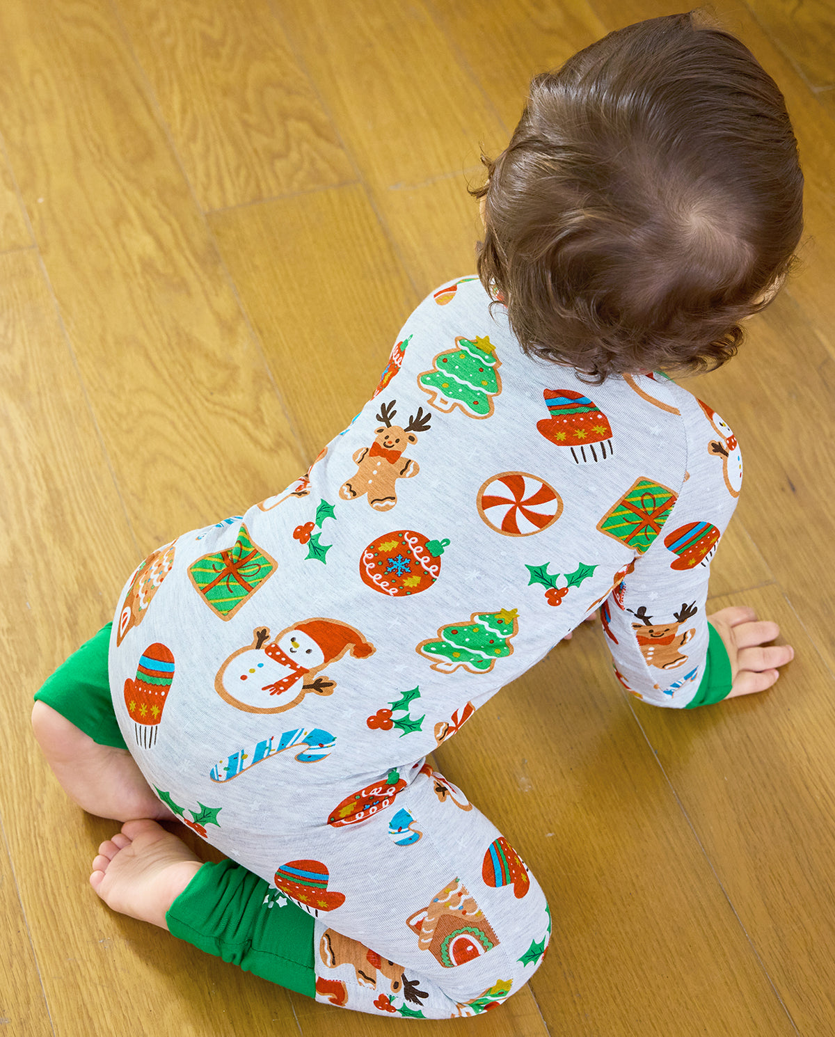 Overhead back view of a baby crawling in the grey Gingerbread Gala Bamboo Zippy with Christmas cookie motifs