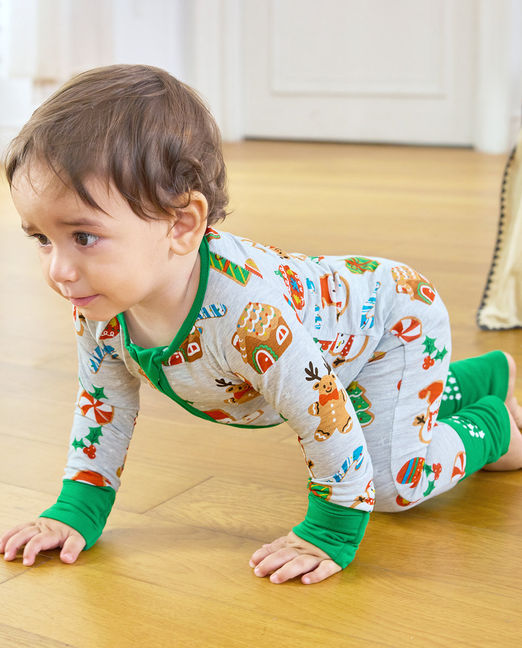 Side view of a crawling baby in the Gingerbread Gala Bamboo Zippy with green convertible foot cuffs
