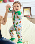 Baby standing with an adult's support in the Gingerbread Gala Bamboo Zippy, showing the green zipper and covered feet