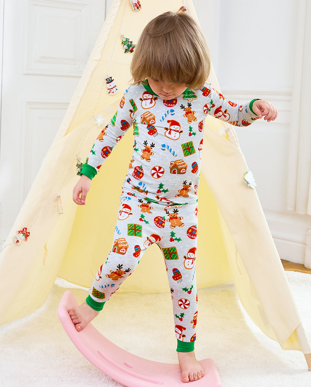 Child standing beside a rocking toy in Gingerbread Gala long-sleeve top and pants