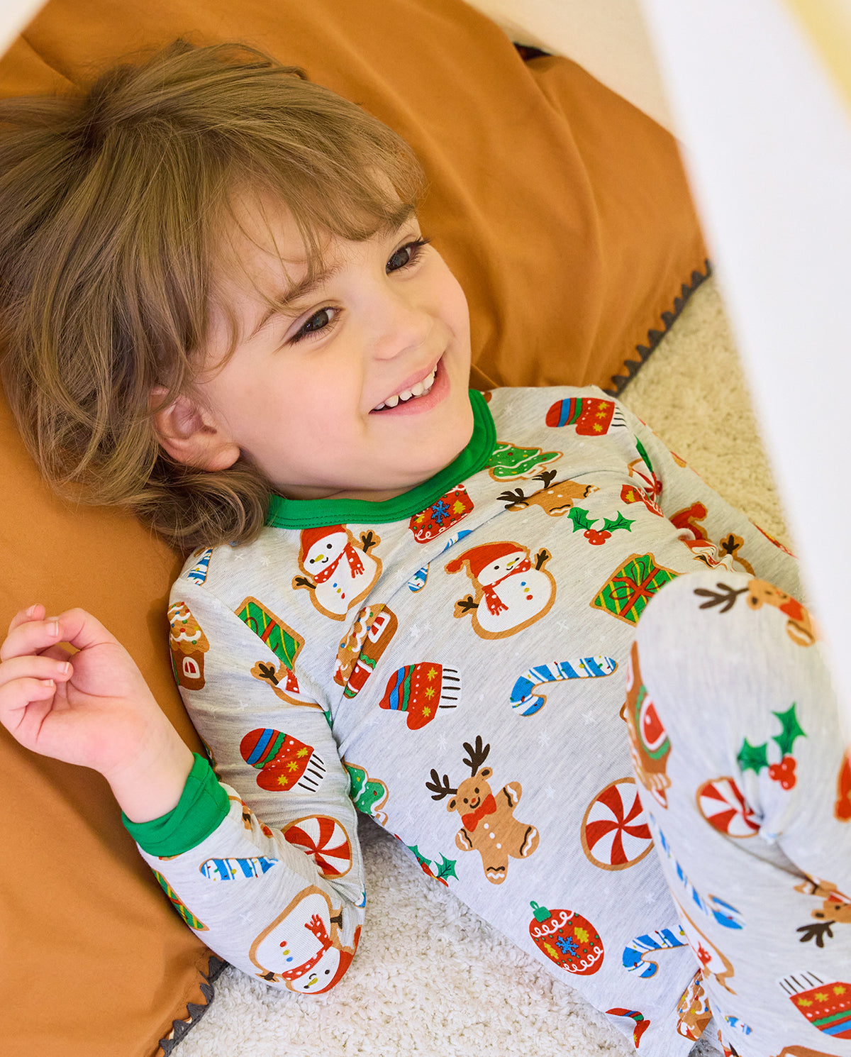 Smiling child reclining on a sofa in Gingerbread Gala holiday pajamas