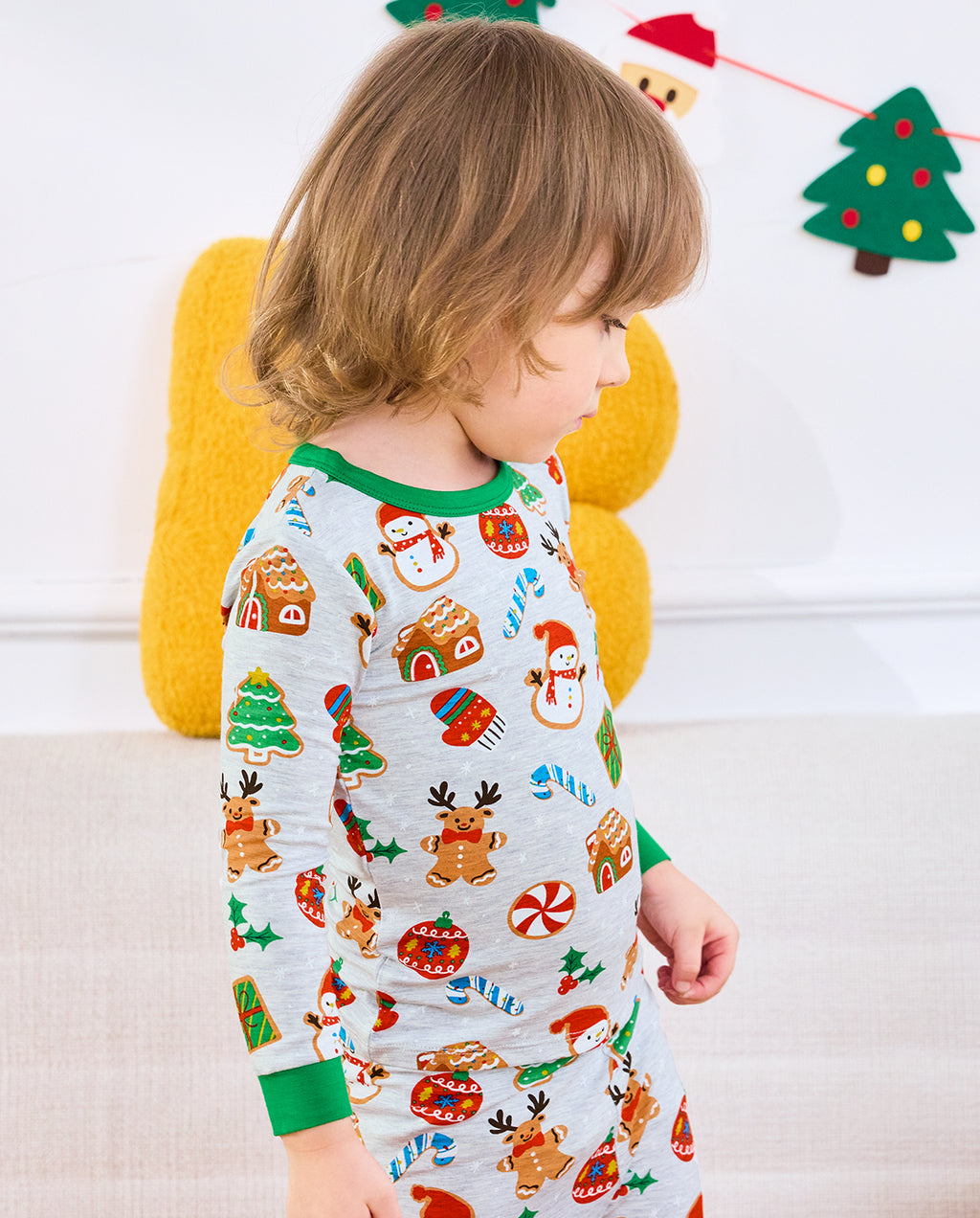 Side view of a child standing in Gingerbread Gala pajamas with green trim