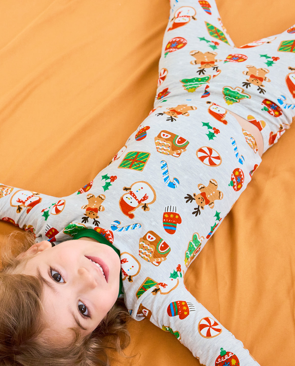 Child lying on a sofa in Gingerbread Gala pajamas showing the festive cookie print