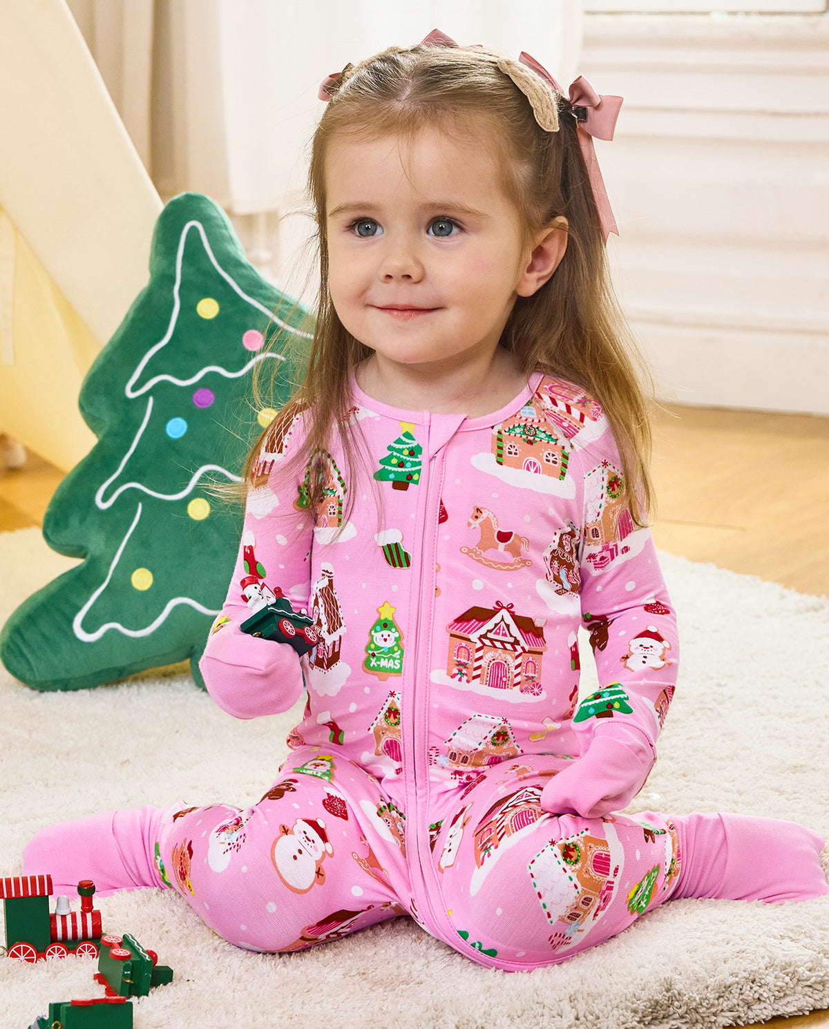 Child seated on a rug holding a toy in the pink Gingerbread Lane romper.