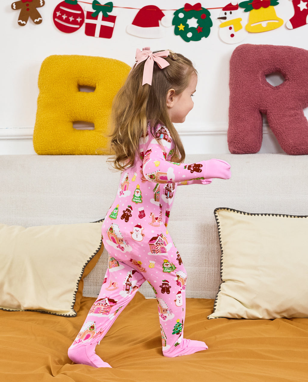Side view of a child standing by a sofa in the Gingerbread Lane romper.