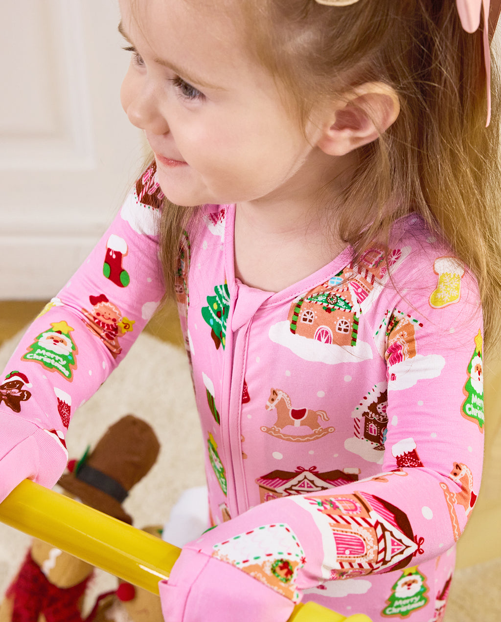 Close view of a child wearing the Gingerbread Lane romper with gingerbread house motifs.