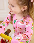 Close view of a child wearing the Gingerbread Lane romper with gingerbread house motifs.