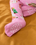 Close-up of pink foot cuffs with white star and dot sole grips on the Gingerbread Lane romper.