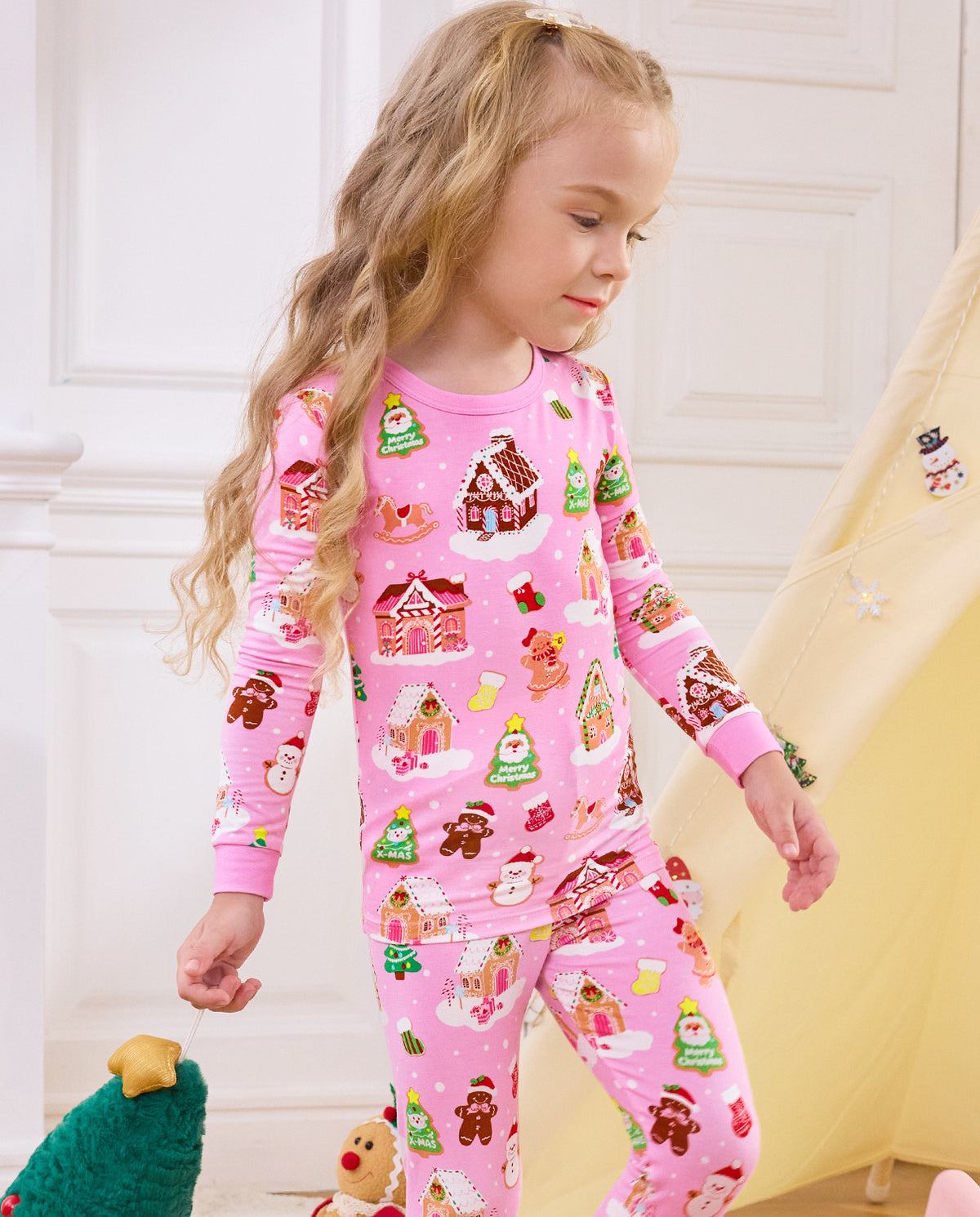 Side view of a child standing beside a tent in Gingerbread Lane pajamas.