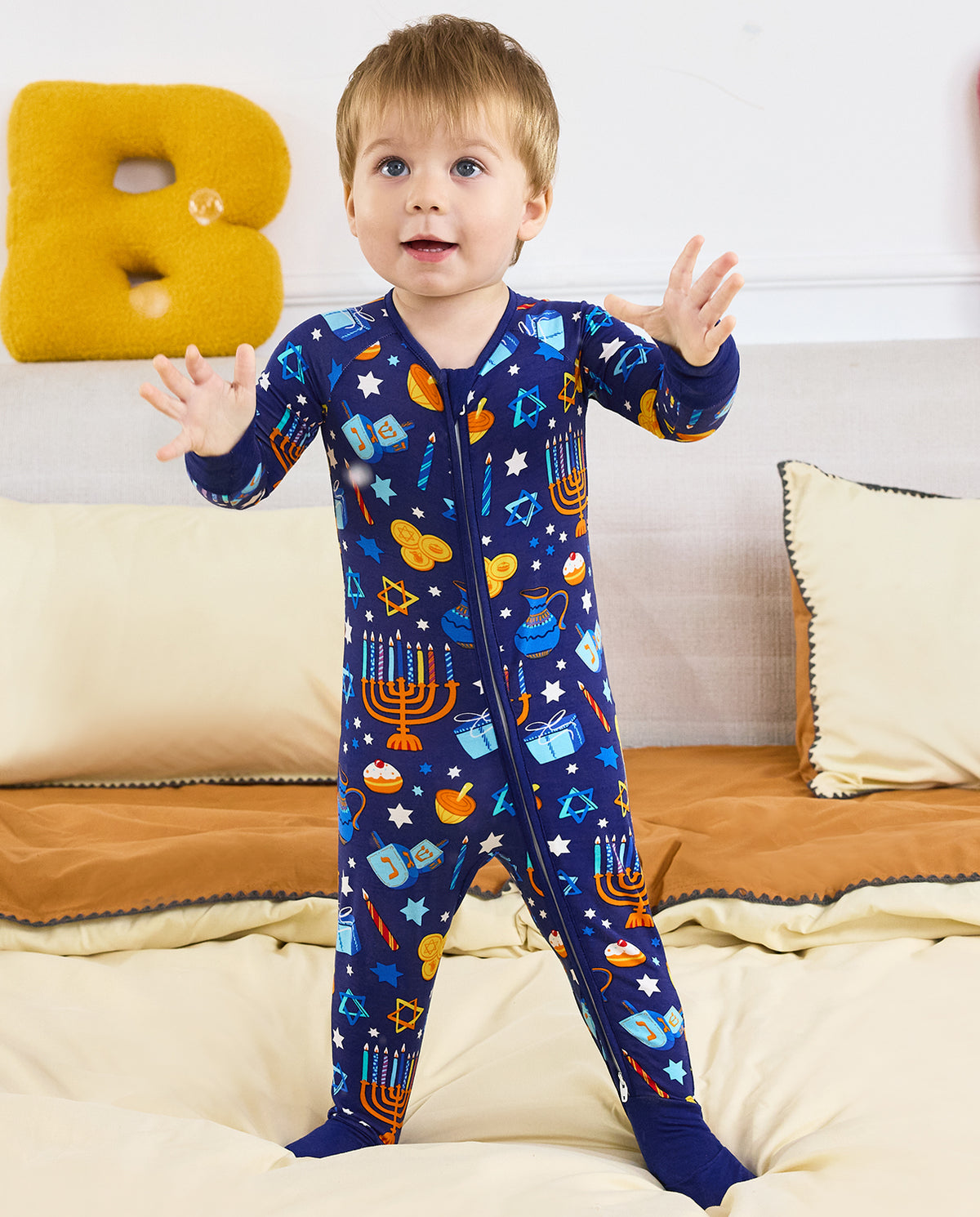 Child standing with arms raised in the navy Hanukkah Magic zip-up romper.