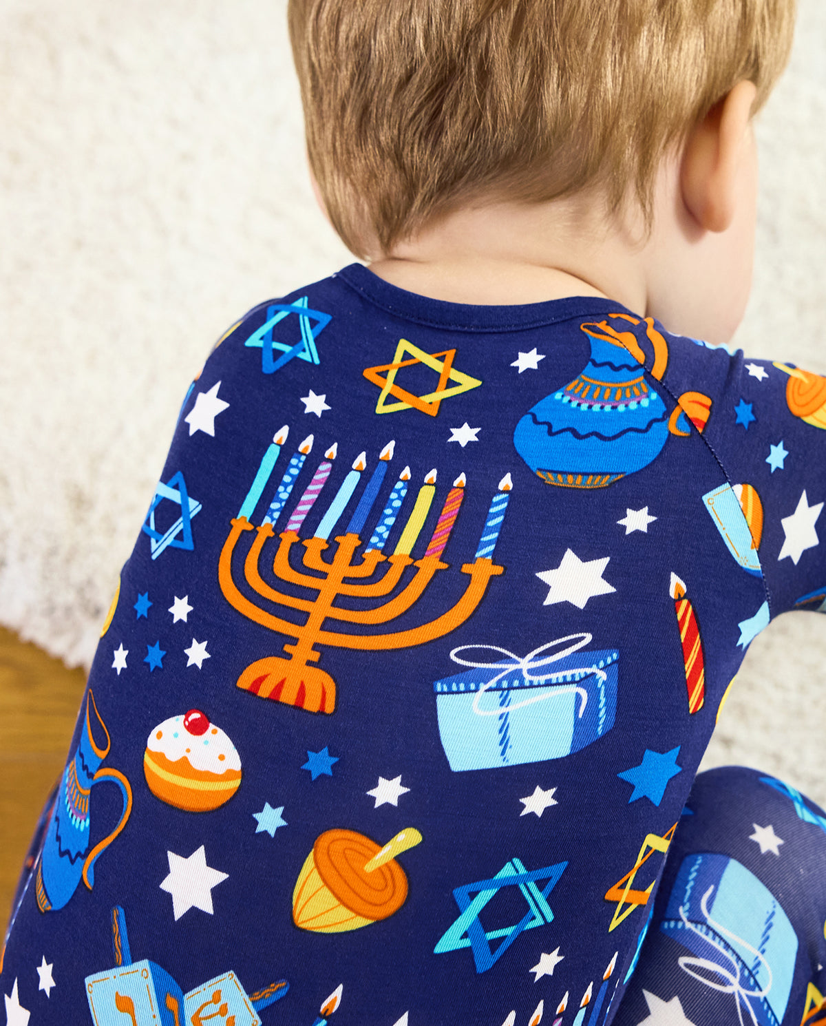 Rear close view of the Hanukkah Magic romper with star, gift and menorah motifs.