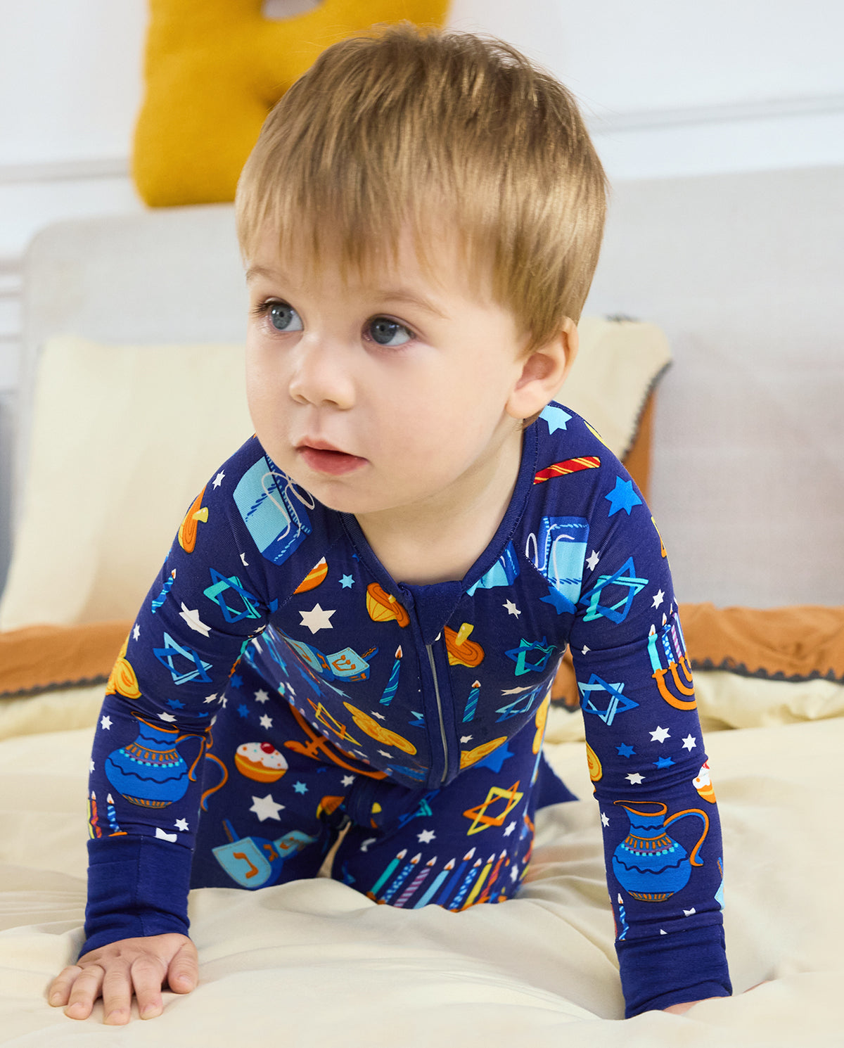 Child leaning forward on bedding in the Hanukkah Magic romper.