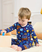 Child seated beside a wooden toy box in the Hanukkah Magic two-piece pajama set.
