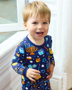 Close front view of a smiling child in the Hanukkah Magic long-sleeve top.